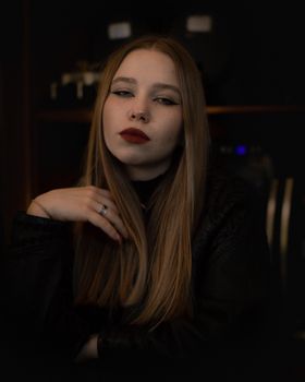 Elegant portrait of a young woman with striking red lips in a dark setting.