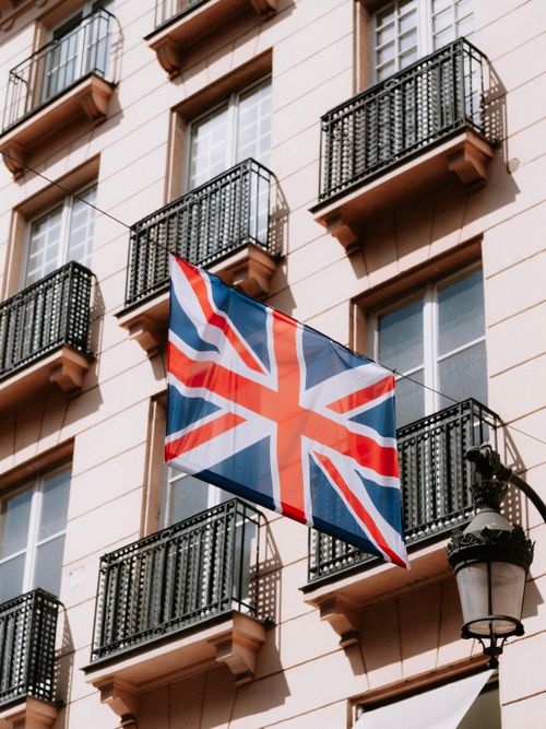 Free Close-up of British flag hanging from a classic European building with balconies. Stock Photo