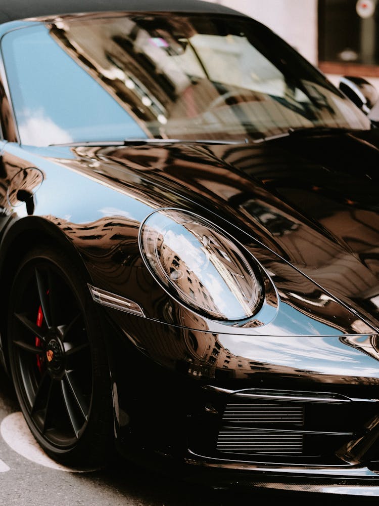 A Shinny Black Car With Reflection Of Building