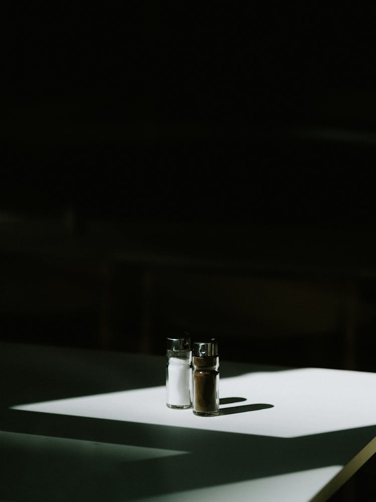 A Pair Of Spices On Glass Dispensers On Table