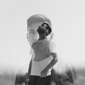 Artistic black and white double exposure of a man looking upwards, creating a surreal effect.