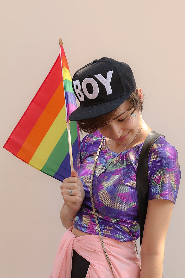 A Person With Black Cap Holding A Rainbow Flag