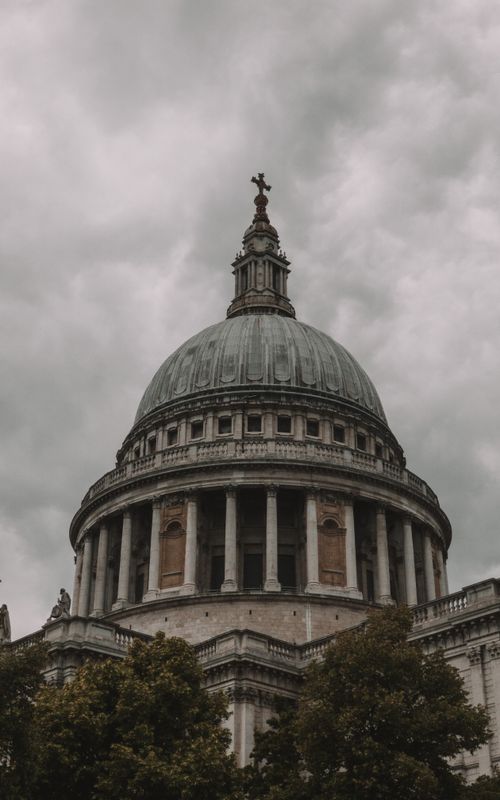 Free A low-angle view of St. Peter's Cathedral dome under a cloudy sky, showcasing its architectural grandeur. Stock Photo