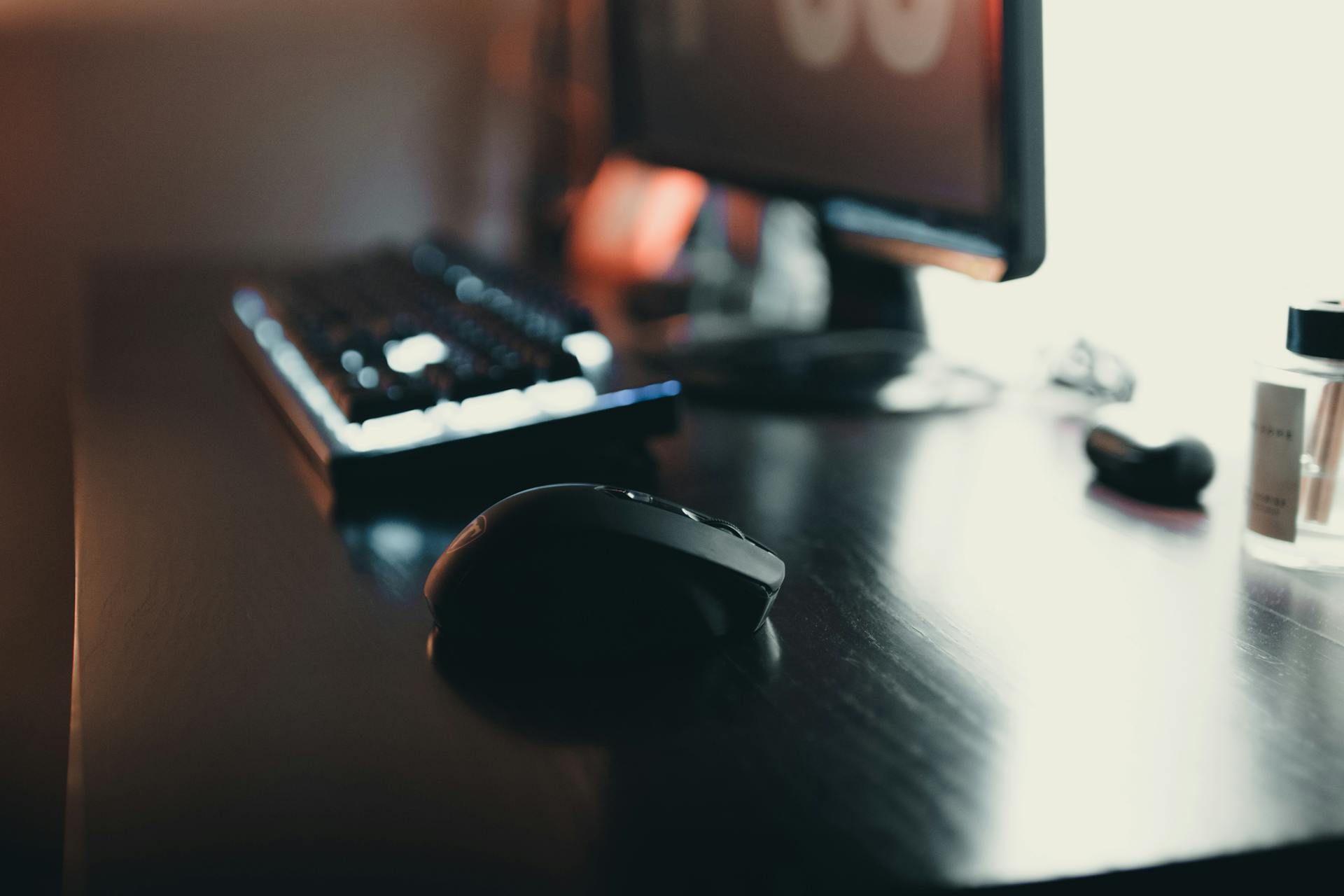 Close-up of a sleek desk setup featuring a keyboard, mouse, and monitor.