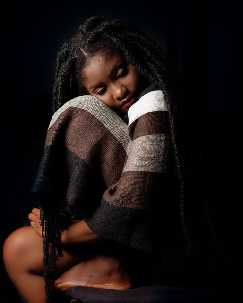 Free Elegant portrait of a woman wrapped in a blanket, sitting serenely. Stock Photo