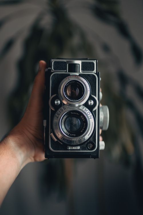 Free Close-up of a hand holding a vintage analog camera with artistic bokeh effect. Stock Photo