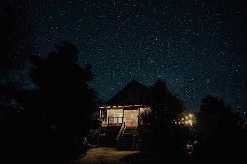 Illuminated House Under a Starry Night Sky