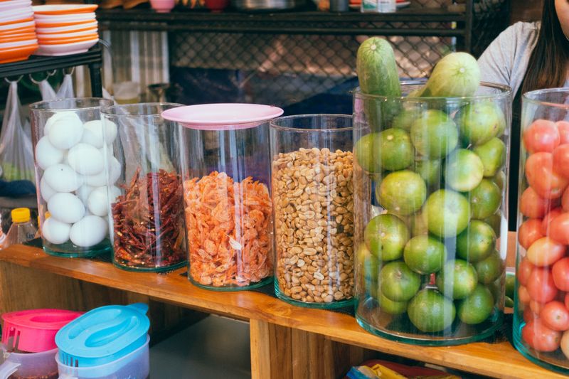 Colorful market display with eggs, dried shrimp, peanuts, green vegetables in Bangkok shop.