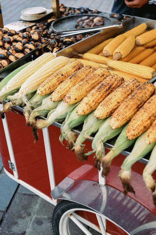 Free Freshly grilled corn displayed on a street vendor cart, perfect for summer market scenes. Stock Photo