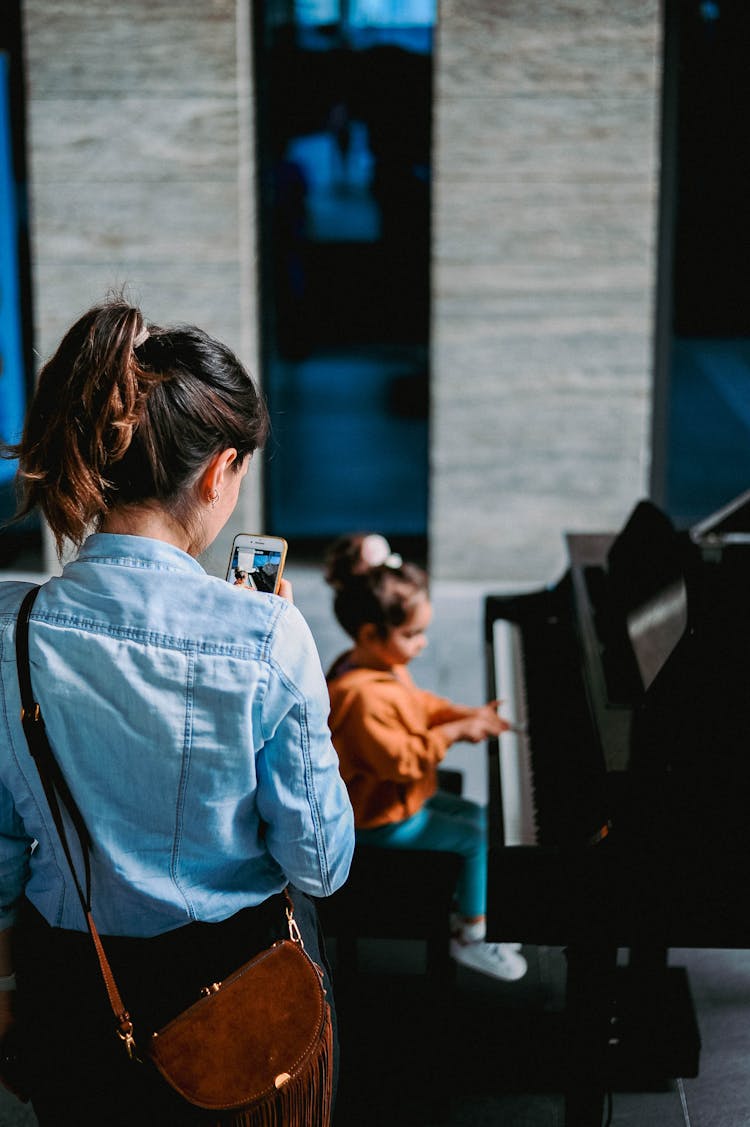 Woman Photographing Girl Playing Piano