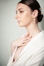 Woman in White Sleeveless Dress Wearing Silver Flower Earrings