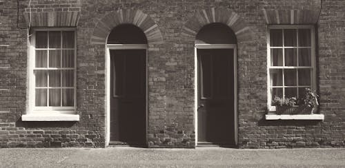 Brown Doors Near  Windows of a Gray Brick Building