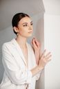 Woman in White Blazer Leaning on White Wall
