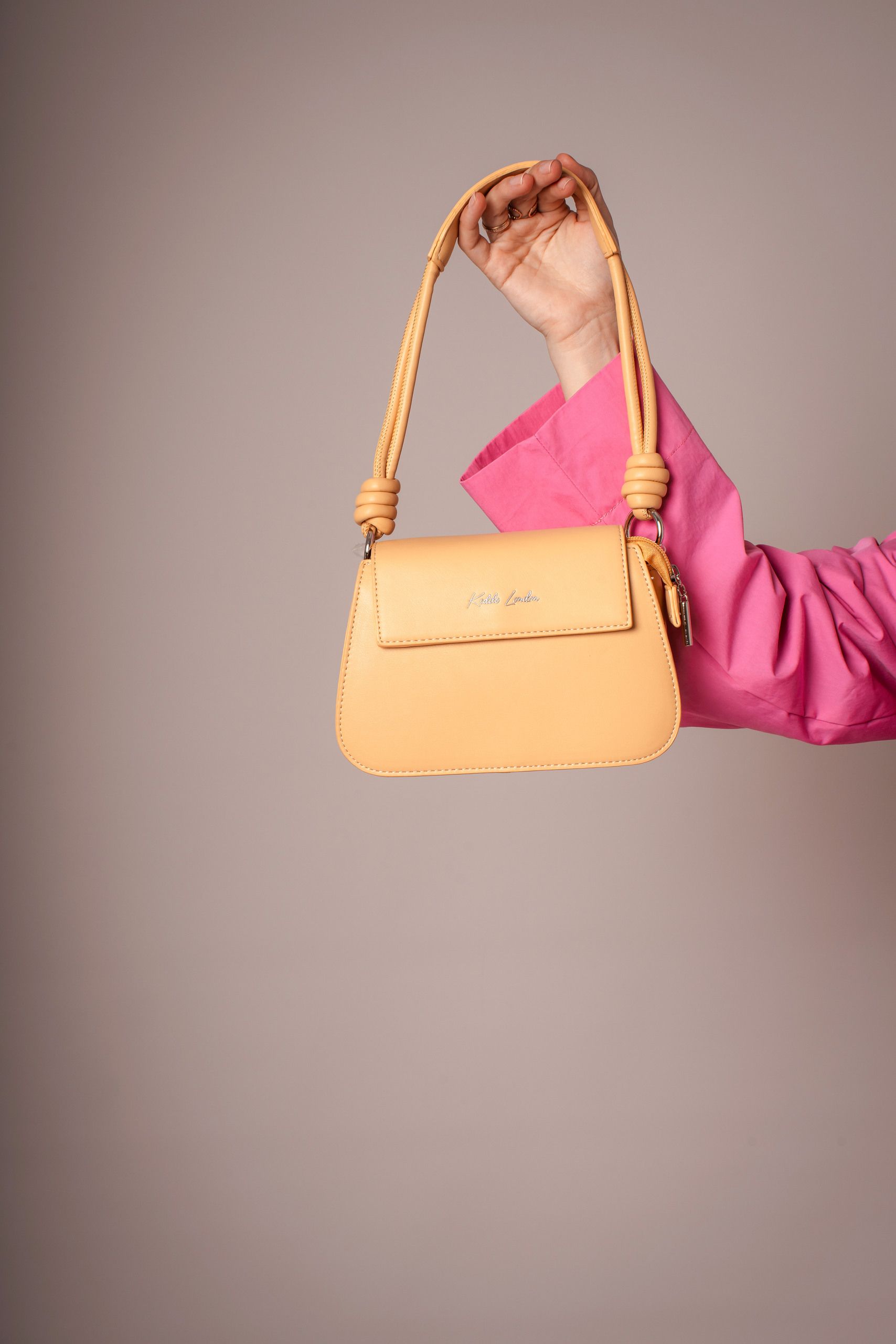 Close-up of a woman holding a structured fashion handbag against a clean neutral background