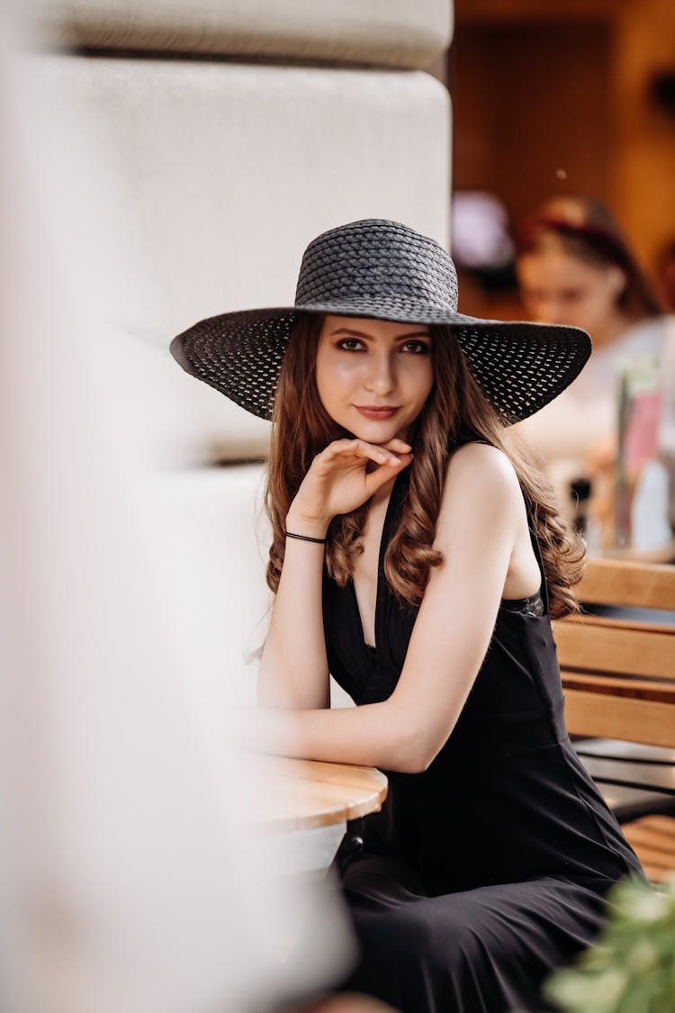 Woman Wearing A Black Dress And Black Round Hat