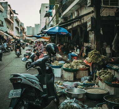 Busy street market in Cambodia with motorcycles and fresh produce vendors.