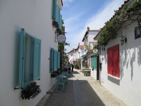 A picturesque alley with vibrant shutters and tables, perfect for a stroll.