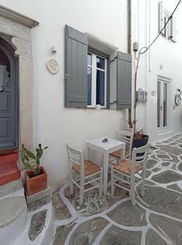 A quaint outdoor café in a whitewashed Greek alley with rustic charm.