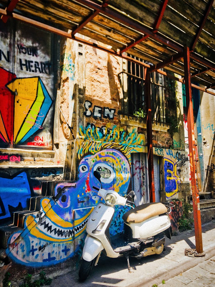 A Scooter Parked Beside A Graffiti Wall