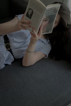 A woman leisurely reading on a sofa, creating a serene and relaxed atmosphere indoors.