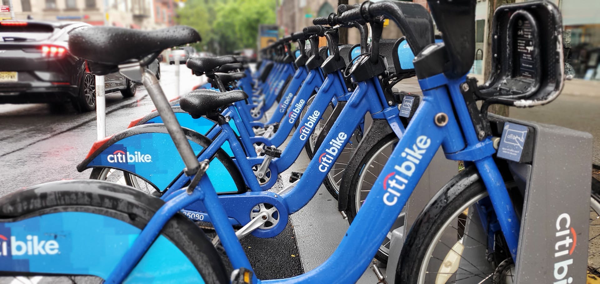 Row of parked Citi Bikes in Brooklyn, NY, during a rainy day.