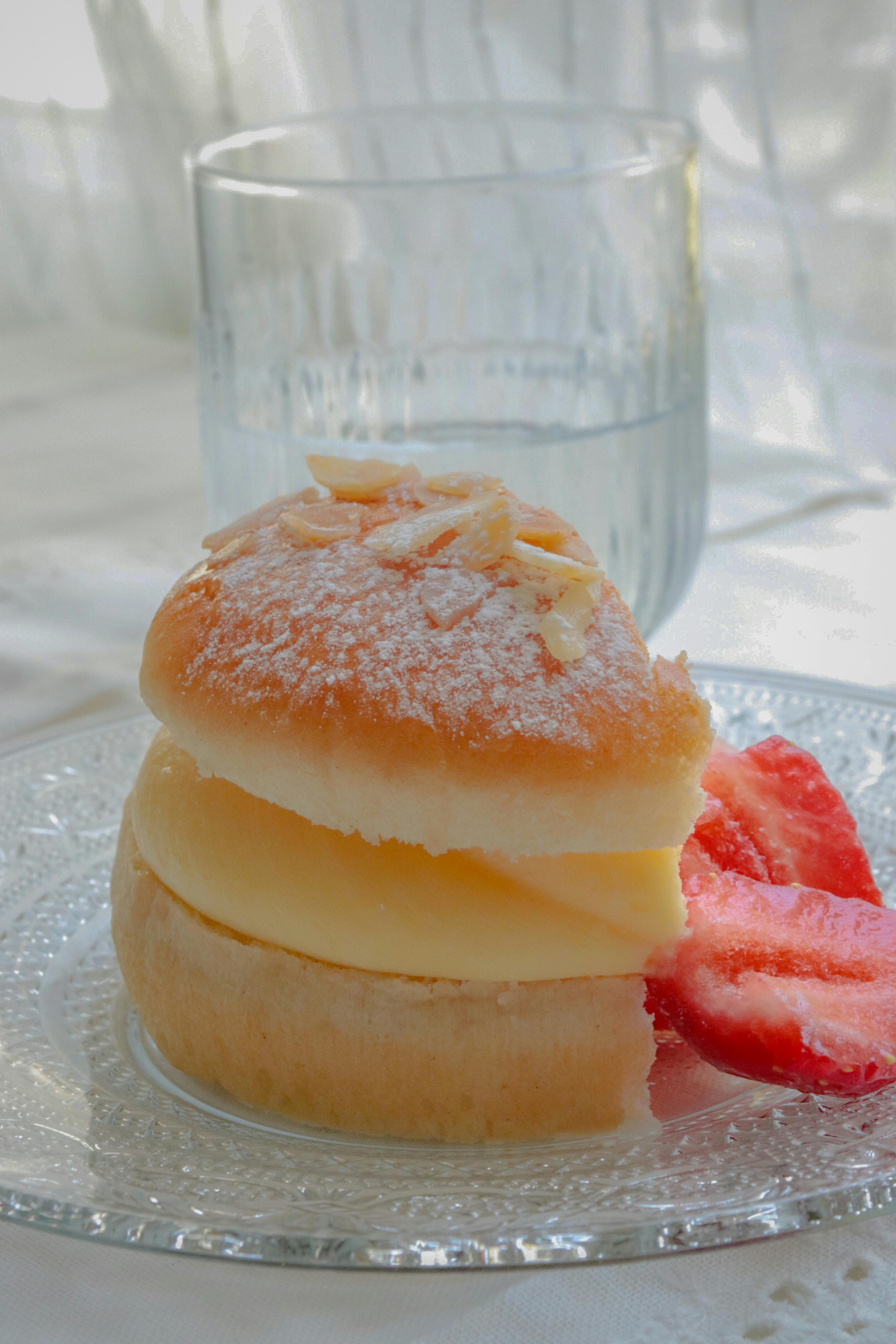 Close-up of a delectable sweet bun with cream filling and fresh strawberries, perfect dessert.