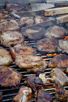 Juicy pork steaks sizzling on a hot barbecue grill outdoors, perfect for summer cookouts.