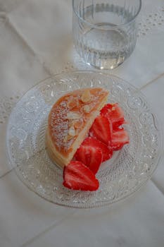 A delectable French dessert featuring pancakes and strawberries served on a glass plate.