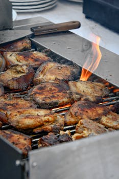 Juicy grilled pork chops sizzling on an open barbecue grill with visible flames.