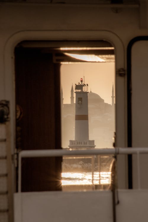 A White and Red Lighthouse with a View from a Ship Doorway