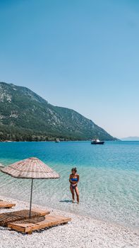 Woman in bikini enjoying a sunny day at the seaside with clear blue waters.