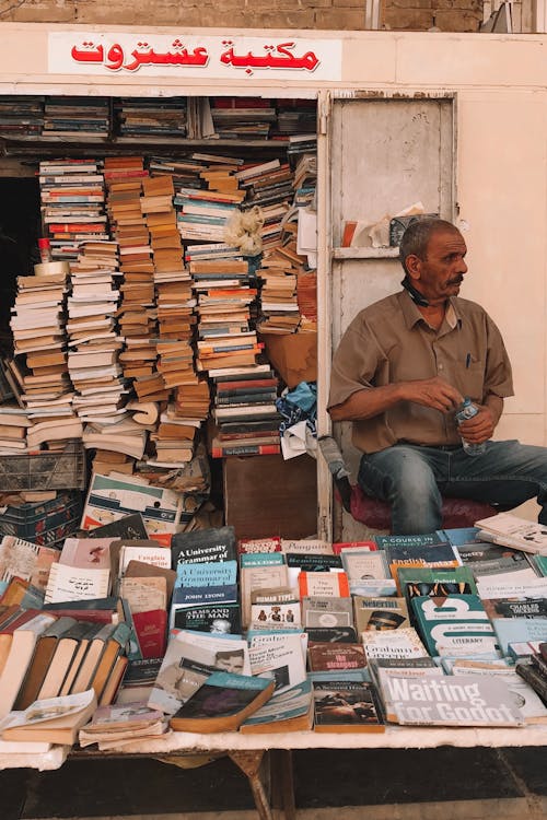 A Man Sitting Beside Books on Sale 