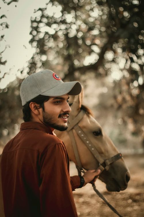Free A man in a cap stands beside a horse in a serene, autumn outdoor setting. Stock Photo