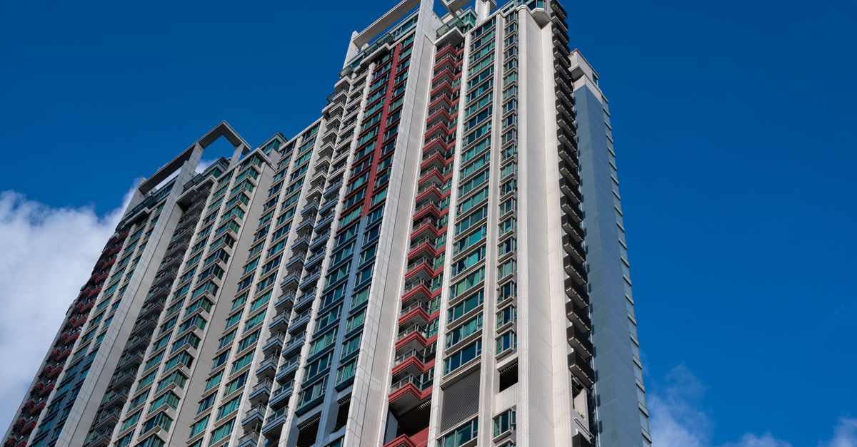 Low angle view of a modern skyscraper with glass facade under clear blue sky.