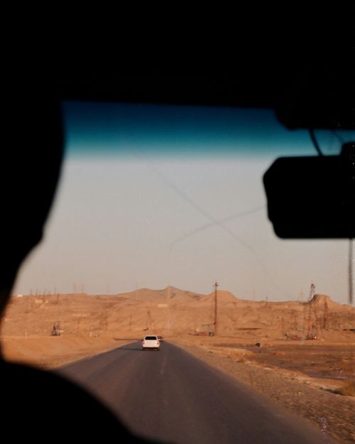 Free View from a car on a long empty road through a desert landscape under a clear sky. Stock Photo