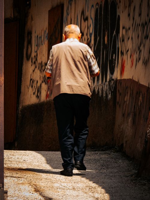Free A man walks through a narrow, graffiti-lined alleyway in an urban setting. Stock Photo