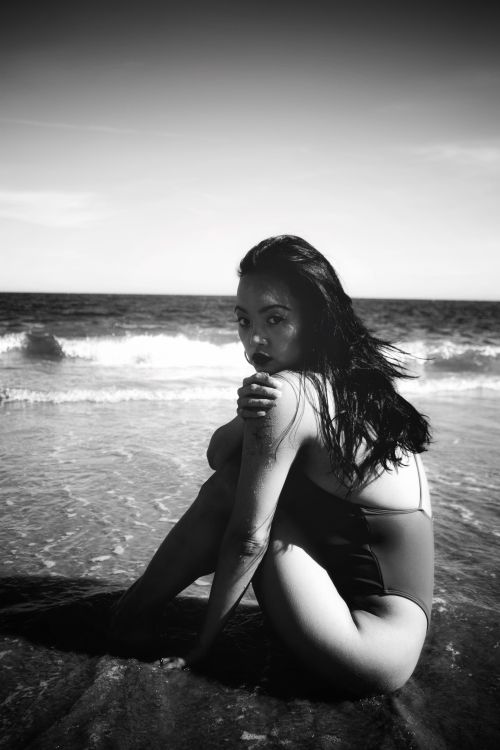 Free Striking monochrome image of a woman posing by the seaside, evoking a serene yet bold mood. Stock Photo