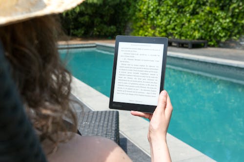 Woman Sitting Beside Pool Holding Tablet 