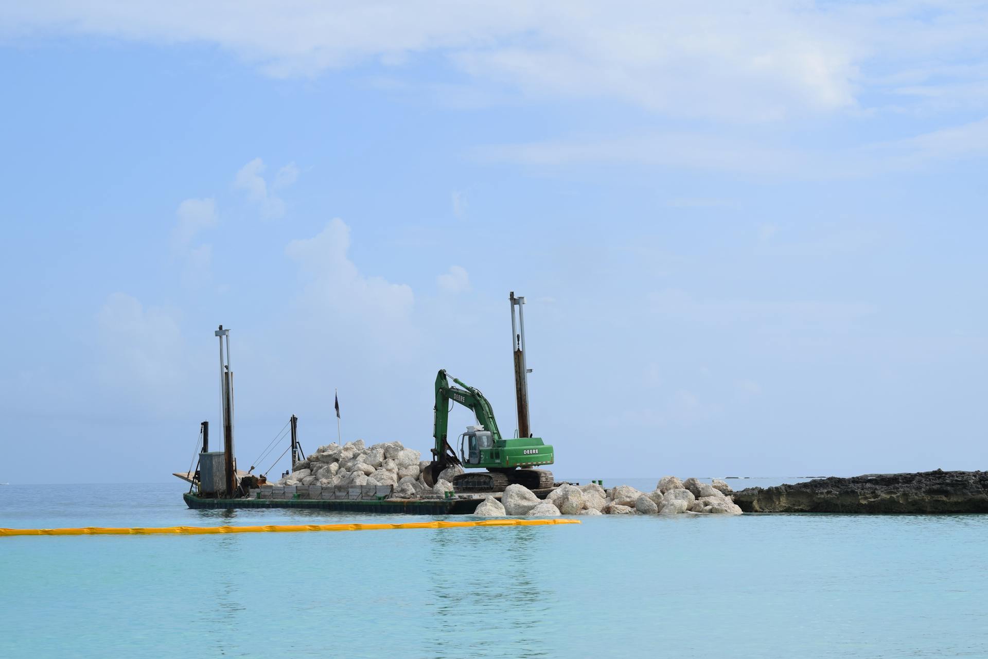 Heavy machinery on a barge handling construction by the sea in New Providence, The Bahamas.