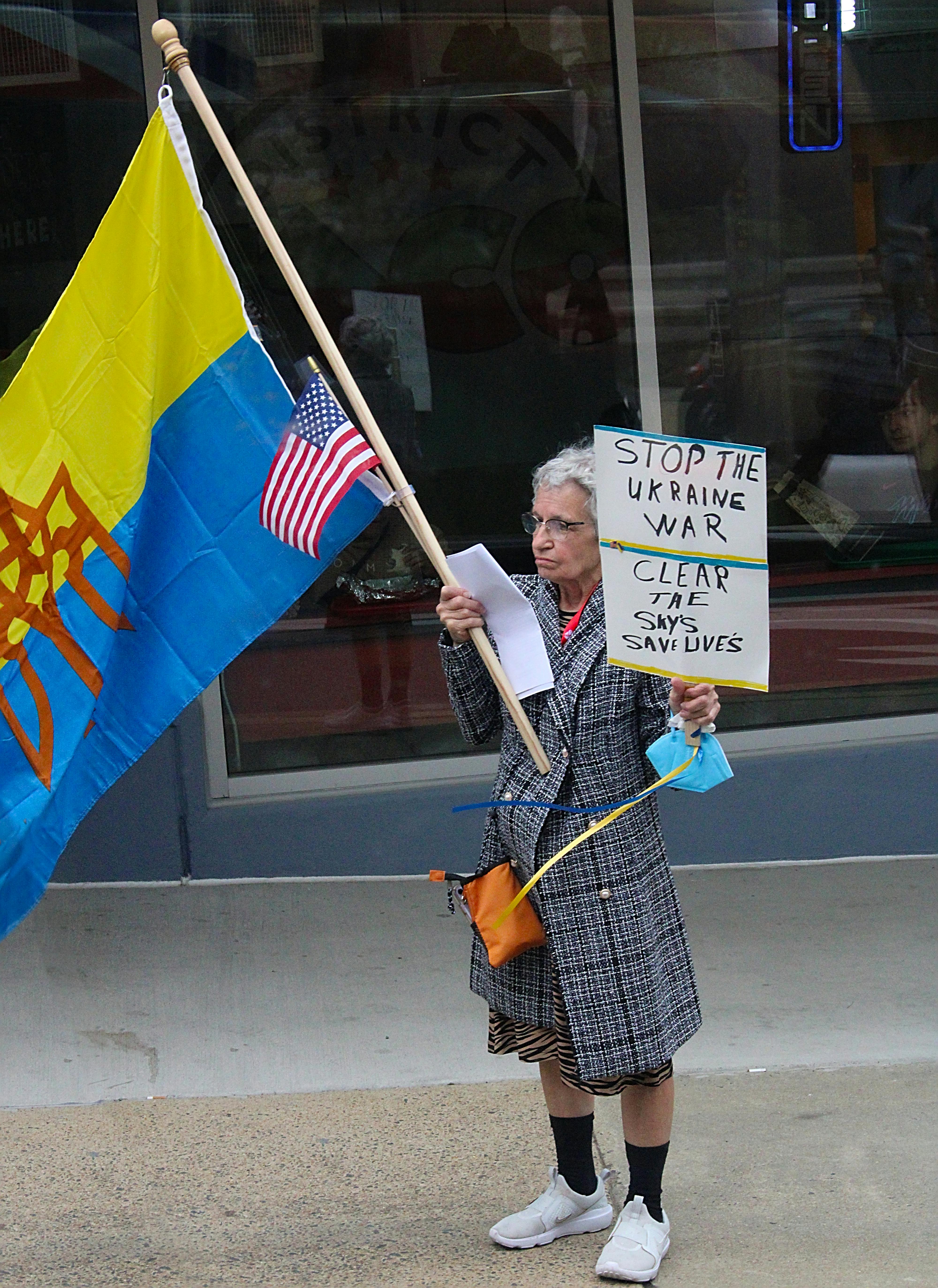 Senior woman holding placard and flags in a protest against the Ukraine war.