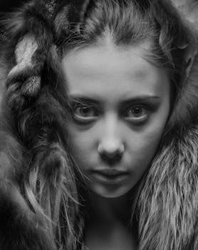 这幅引人注目的黑白肖像中，一位身着毛皮的女性，双眼炯炯有神，衣物质感柔软