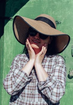 Smiling woman in sunglasses and wide-brimmed hat enjoying a sunny day outdoors.