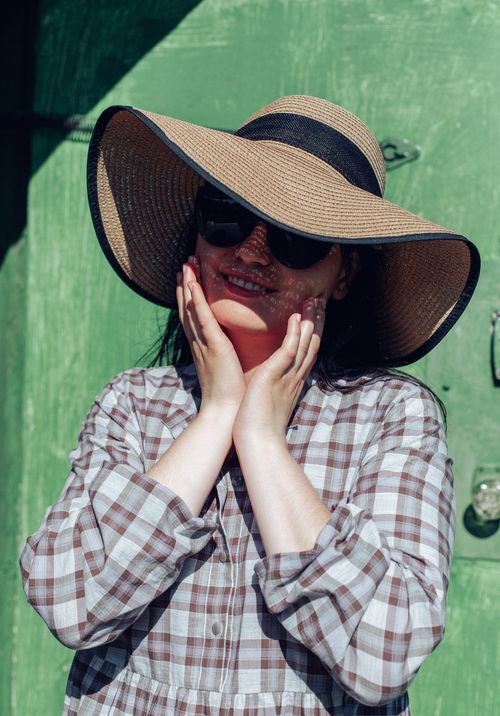 Free Smiling woman in sunglasses and wide-brimmed hat enjoying a sunny day outdoors. Stock Photo