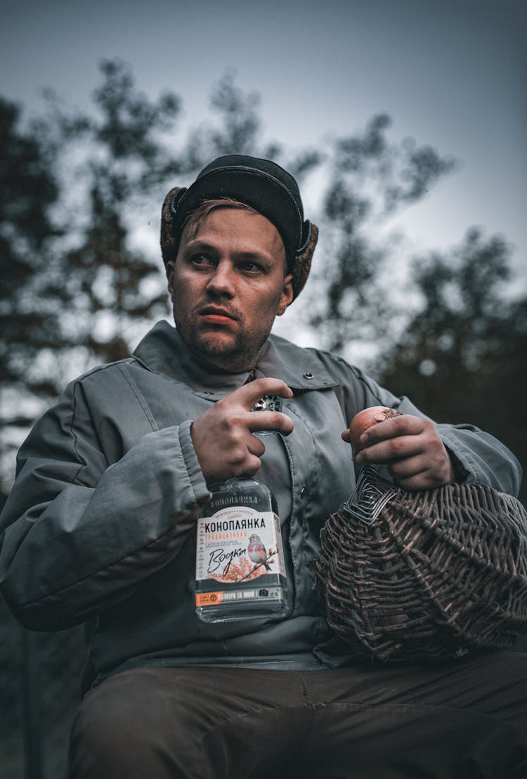 A Man Sitting With A Bottle Of Alcohol