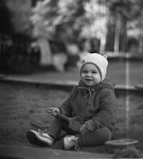 A Grayscale of a Baby Wearing a Jacket and a Bonnet
