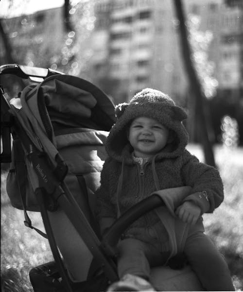 A Grayscale of a Baby Sitting on a Stroller