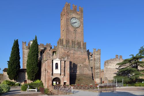 Free Capture of an ancient brick castle featuring a prominent clock tower against a clear blue sky. Stock Photo