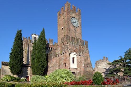 Free Majestic medieval castle with a clock tower surrounded by cypress trees in Italy. Stock Photo