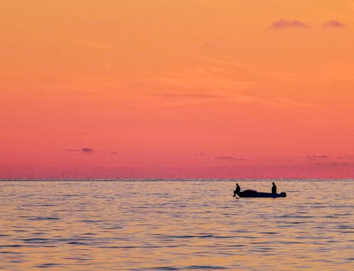 Silhouette of Men on a Boat During Sunset