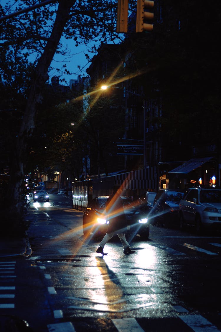 A Person Crossing A Road At Night